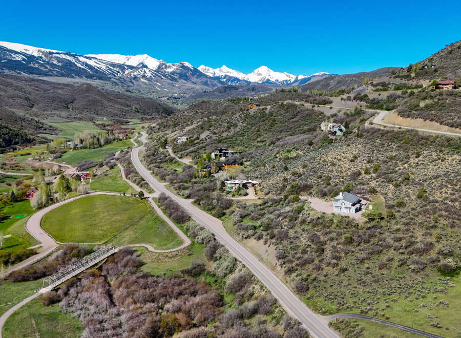 Discover luxury mountain living with this stunning aerial view of a sprawling estate nestled amidst breathtaking snow-capped peaks.