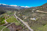 Discover luxury mountain living with this stunning aerial view of a sprawling estate nestled amidst breathtaking snow-capped peaks.