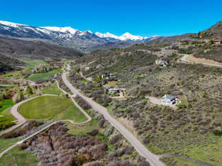 Discover luxury mountain living with this stunning aerial view of a sprawling estate nestled amidst breathtaking snow-capped peaks.