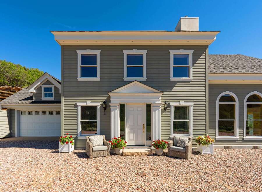 Charming home with a welcoming entrance, featuring a white double door and elegant columns.