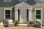 Charming home featuring a welcoming entrance with a classic white door, flanked by elegant fluted columns and decorative pediment.