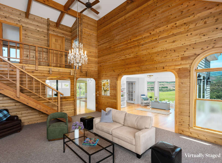 Experience rustic charm in this stunning living room, featuring soaring wood-paneled walls and a grand chandelier.