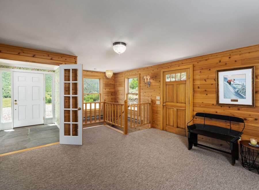 Step into a charming mountain retreat featuring warm wood paneling throughout and a welcoming entryway.