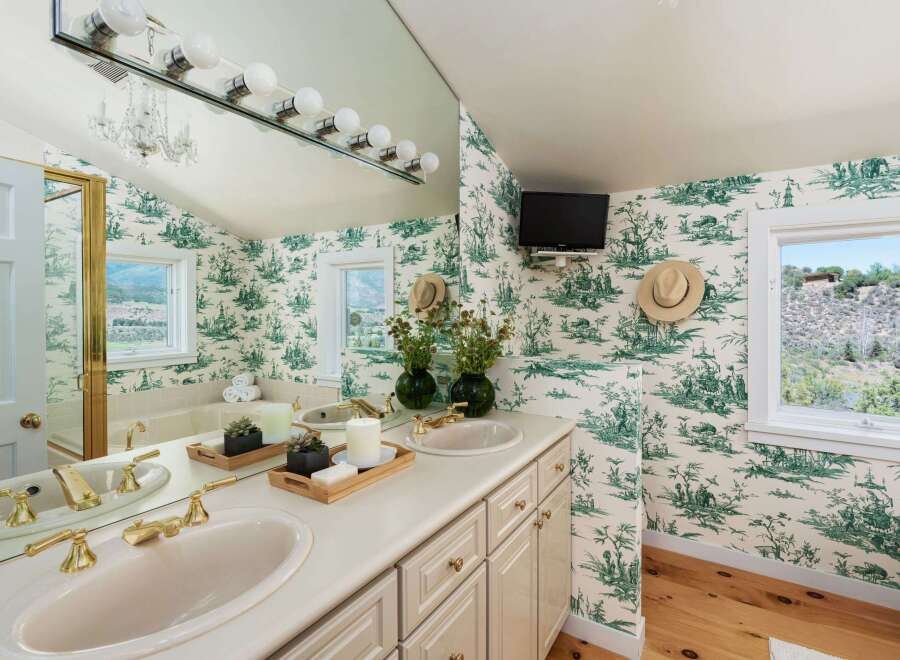 This charming bathroom features a double vanity with elegant gold fixtures and a large mirror, perfect for morning routines.