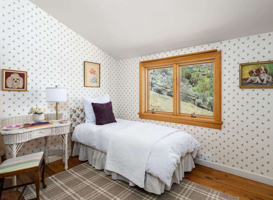 Charming bedroom featuring a cozy twin bed with a white quilted comforter and a decorative purple pillow.