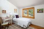 Charming bedroom featuring a cozy twin bed with a white quilted comforter and a decorative purple pillow.
