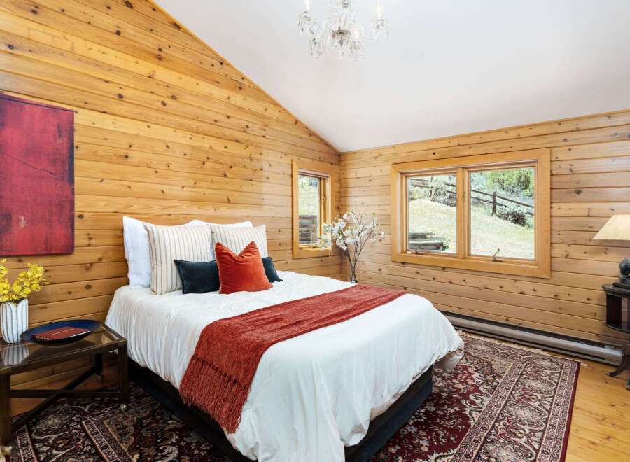 Experience rustic charm in this cozy bedroom featuring warm wood-paneled walls and a vaulted ceiling.