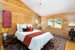Experience rustic charm in this cozy bedroom featuring warm wood-paneled walls and a vaulted ceiling.