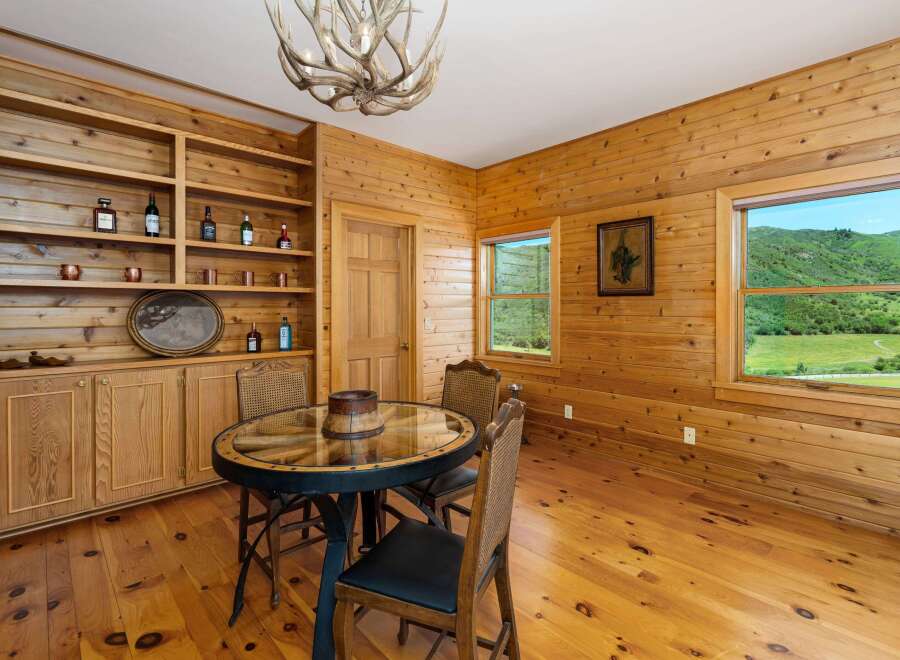 Experience rustic charm in this dining area featuring warm, knotty pine wood paneling throughout.