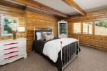 Experience rustic charm in this cozy bedroom featuring warm wood-paneled walls and exposed beams.