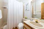 This charming bathroom features a light-colored tiled shower and tub area, complemented by a crisp white shower curtain.