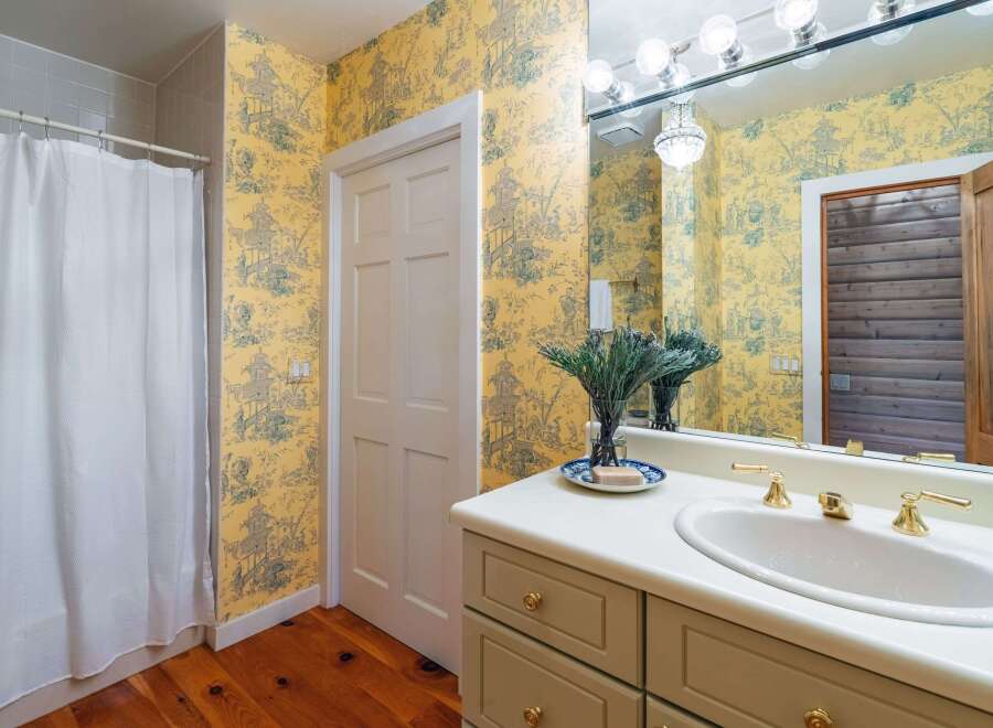 This charming bathroom features a vibrant yellow toile wallpaper that adds a touch of classic elegance.