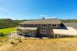 Nestled amidst rolling green hills and under a clear blue sky, this stunning property offers a serene retreat.