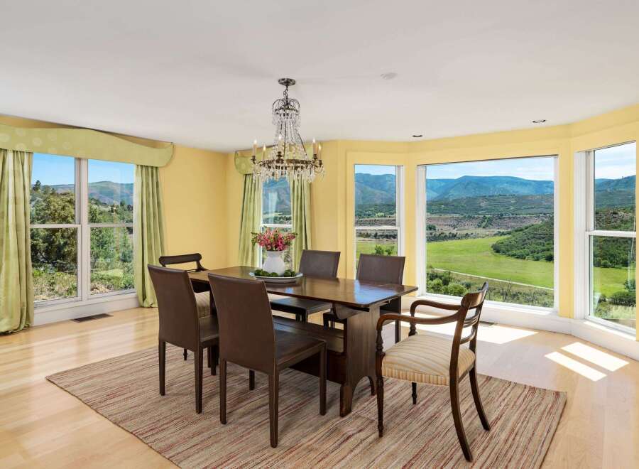 Enjoy breathtaking mountain views from this elegant dining room, featuring a large wooden table with comfortable seating and a stunning crystal chandelier.
