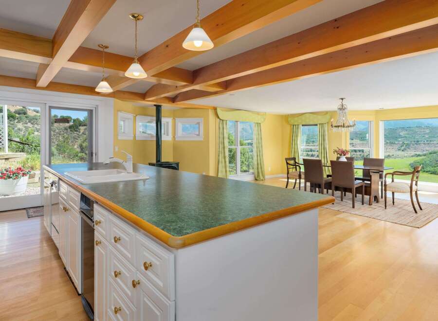 Experience breathtaking panoramic views from this stunning kitchen and dining area, featuring a spacious island with a sink and ample cabinet space.
