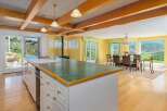 Experience breathtaking panoramic views from this stunning kitchen and dining area, featuring a spacious island with a sink and ample cabinet space.