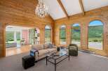 Experience breathtaking mountain views from this stunning living room, featuring a vaulted wood-paneled ceiling and a grand crystal chandelier.