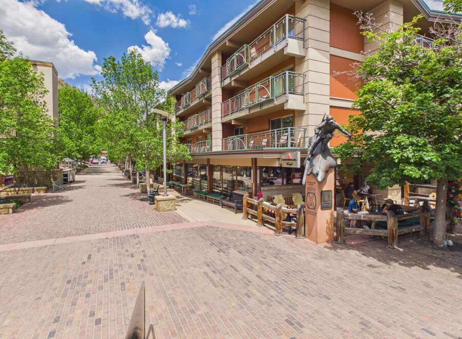 Discover this charming property featuring a multi-story building with balconies overlooking a picturesque brick-paved street lined with trees.