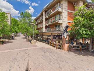 Discover this charming property featuring a multi-story building with balconies overlooking a picturesque brick-paved street lined with trees.