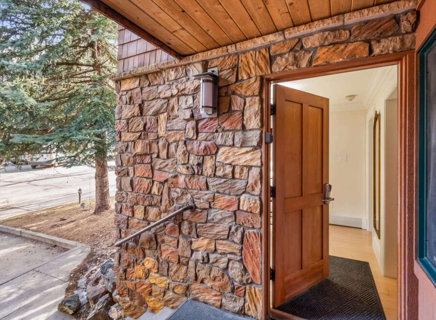 Step into this charming home through a beautiful wooden door, set against a rustic stone exterior.