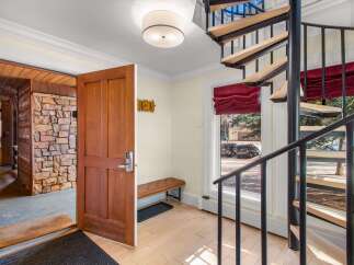 Step into this inviting entryway featuring a rustic stone accent wall and a warm wooden door with a modern digital lock.