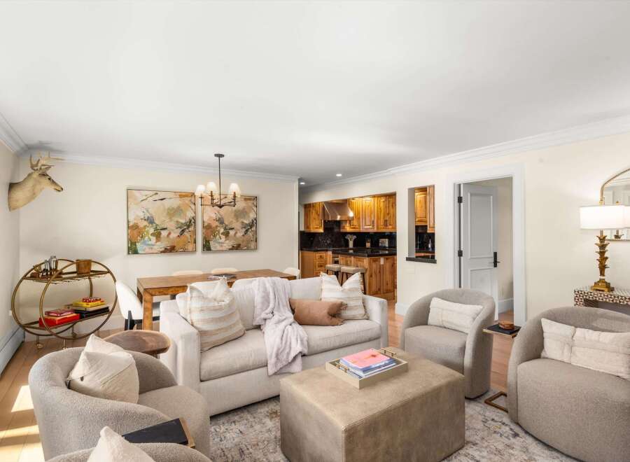 This inviting living space features a plush sofa adorned with decorative pillows and a cozy throw, complemented by two comfortable armchairs.