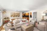 This inviting living space features a plush sofa adorned with decorative pillows and a cozy throw, complemented by two comfortable armchairs.