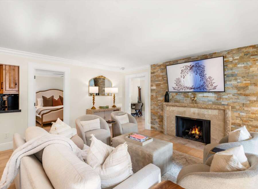 Experience luxury living in this beautifully appointed living room, featuring a cozy fireplace with a stacked stone accent wall and a large flat-screen TV.