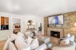 Experience luxury living in this beautifully appointed living room, featuring a cozy fireplace with a stacked stone accent wall and a large flat-screen TV.