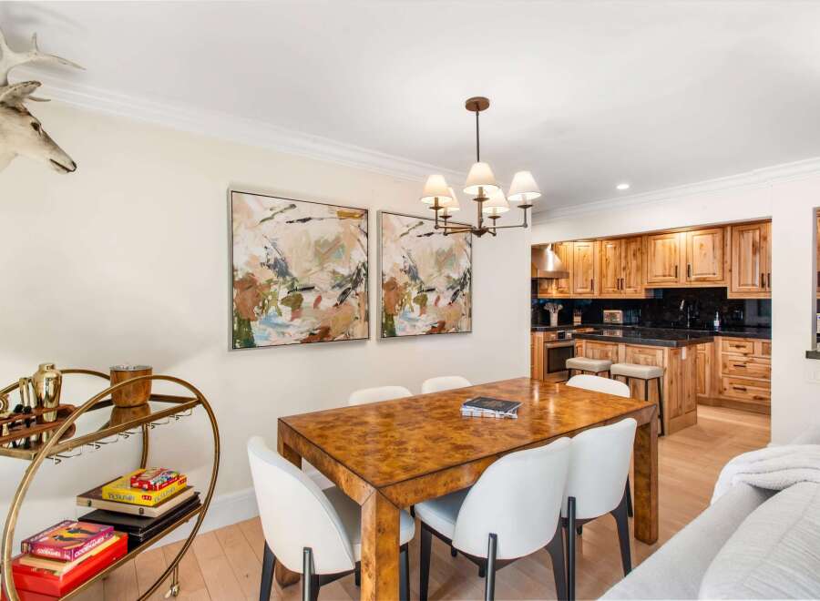 This inviting dining area features a striking burl wood dining table surrounded by elegant white chairs, perfect for intimate gatherings.