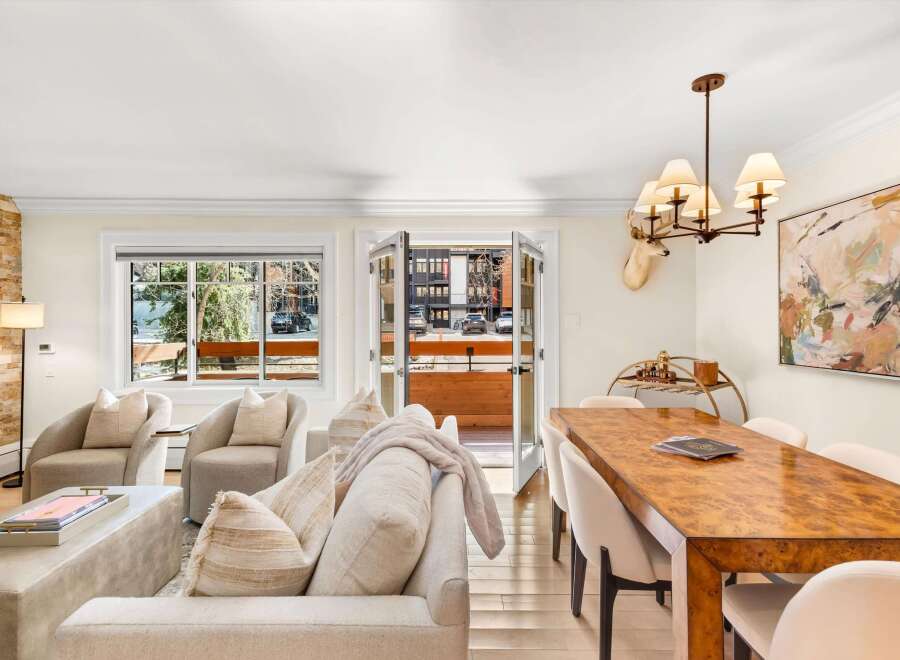 Experience sophisticated living in this elegant dining and living area, featuring a stunning burl wood dining table and plush seating.