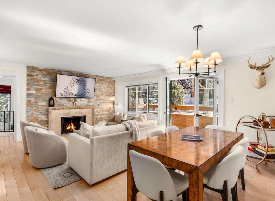 Experience luxurious mountain living in this stunning living and dining area, featuring a cozy stone fireplace and a large flat-screen TV.