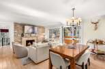 Experience luxurious mountain living in this stunning living and dining area, featuring a cozy stone fireplace and a large flat-screen TV.