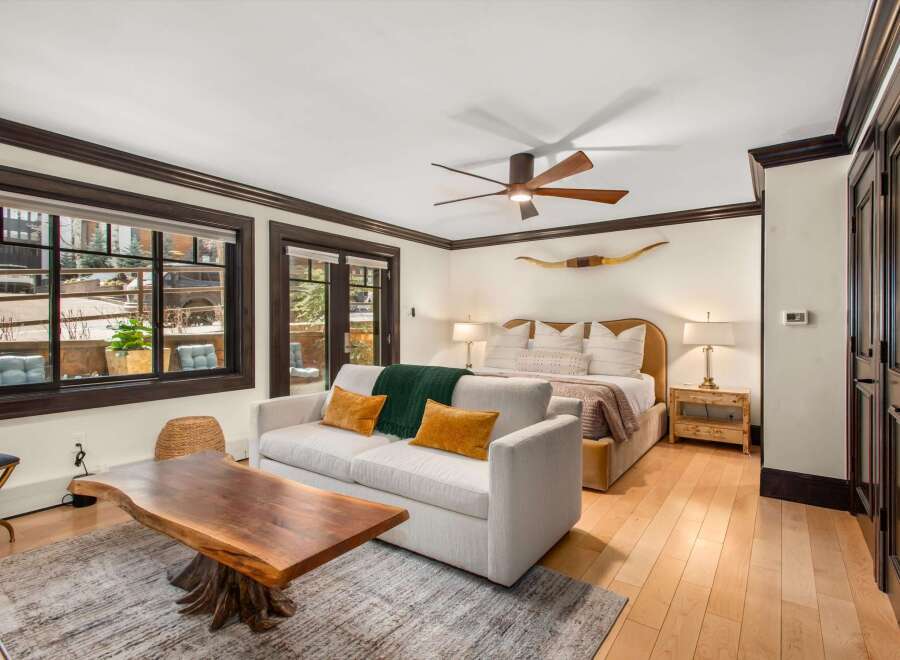 Experience rustic luxury in this spacious bedroom featuring a comfortable king-sized bed adorned with plush pillows and a cozy green throw.