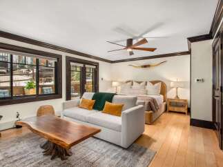 Experience rustic luxury in this spacious bedroom featuring a comfortable king-sized bed adorned with plush pillows and a cozy green throw.