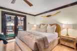 Experience luxurious mountain living in this stunning bedroom featuring a plush king-sized bed adorned with decorative pillows and a cozy throw.