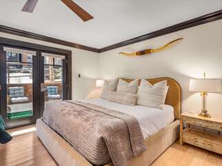 Experience luxurious mountain living in this stunning bedroom featuring a plush king-sized bed adorned with decorative pillows and a cozy throw.