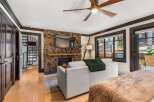 Experience cozy living in this charming room featuring a rustic stone fireplace with a mounted television and a comfortable sofa adorned with a plush green throw.