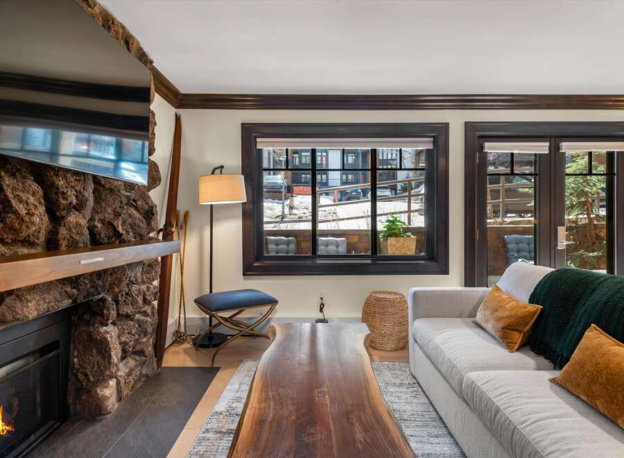 Cozy living room featuring a rustic stone fireplace with a mounted television and a warm wooden mantel.