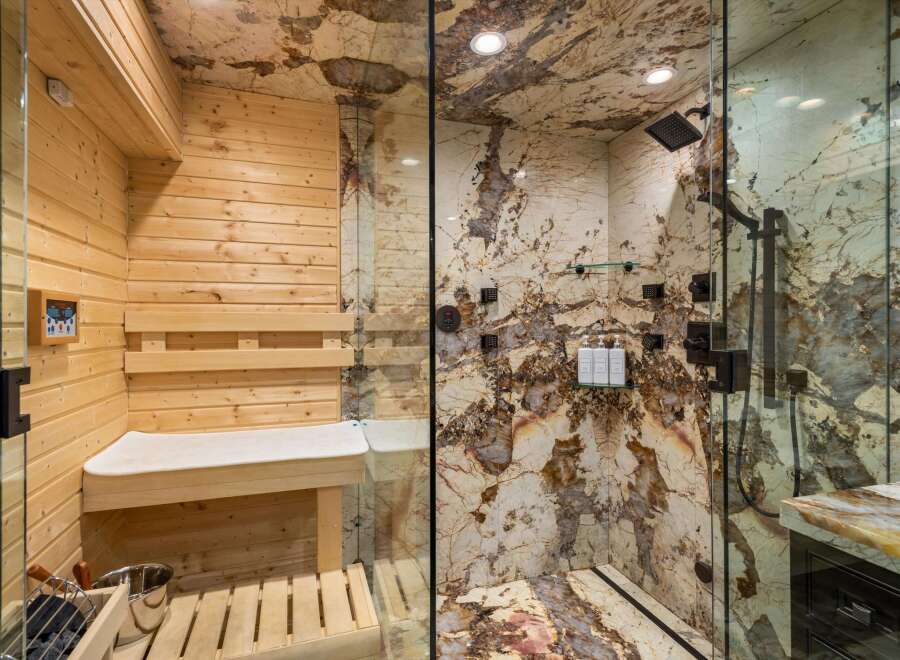 Experience ultimate relaxation in this luxurious spa-like bathroom, featuring a private sauna with wooden interiors and a sleek glass-enclosed shower.