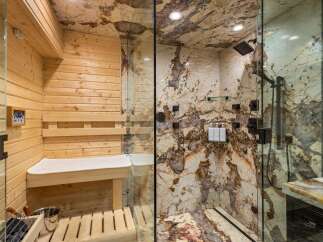 Experience ultimate relaxation in this luxurious spa-like bathroom, featuring a private sauna with wooden interiors and a sleek glass-enclosed shower.