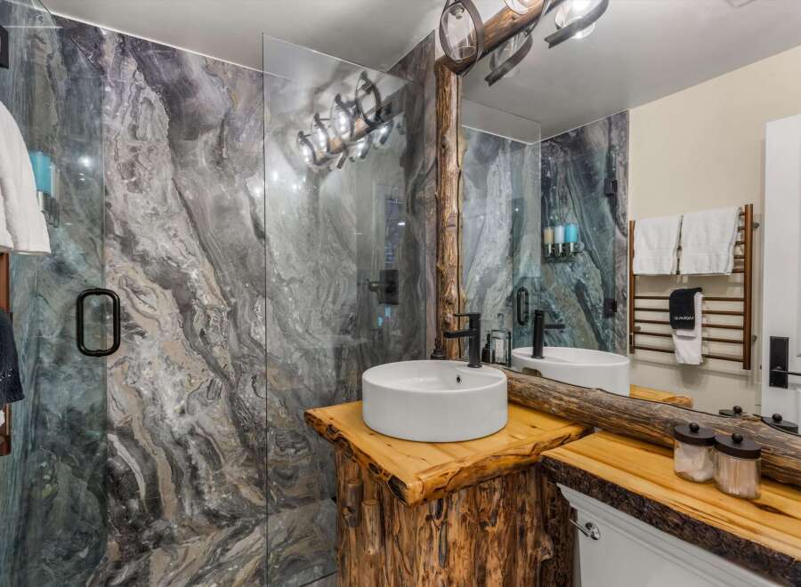 Experience rustic luxury in this stunning bathroom featuring a unique live-edge wood vanity topped with a modern vessel sink and sleek black faucet.