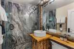 Experience rustic luxury in this stunning bathroom featuring a unique live-edge wood vanity topped with a modern vessel sink and sleek black faucet.