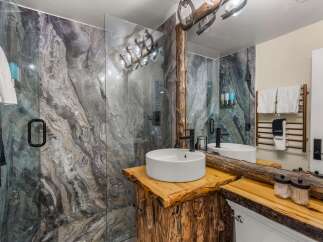 Experience rustic luxury in this stunning bathroom featuring a unique live-edge wood vanity topped with a modern vessel sink and sleek black faucet.