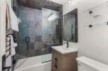 This modern bathroom features a stunning slate tile shower and bathtub surround, complemented by a sleek glass enclosure.