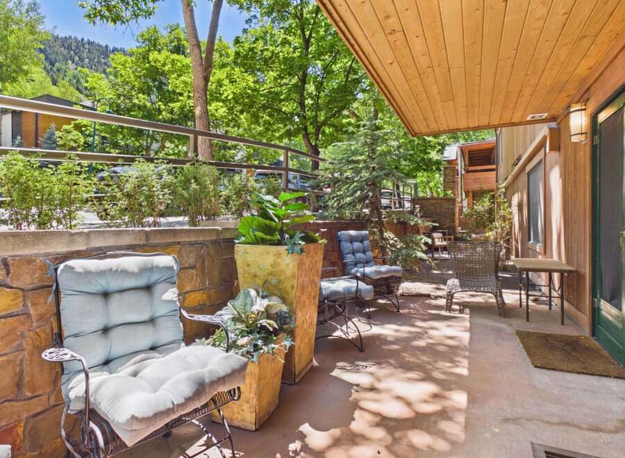 Enjoy the serene outdoor living space on this charming patio, complete with comfortable seating and lush greenery.