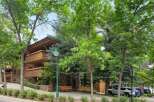 Experience the charm of this multi-story building featuring natural wood siding and stone accents, complemented by ample balconies perfect for enjoying the surrounding greenery.