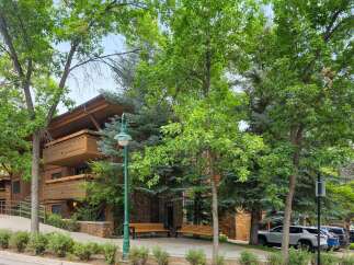 Experience the charm of this multi-story building featuring natural wood siding and stone accents, complemented by ample balconies perfect for enjoying the surrounding greenery.