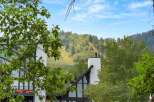 Experience mountain living with this stunning property offering breathtaking views of a lush, tree-covered hillside and a ski slope.