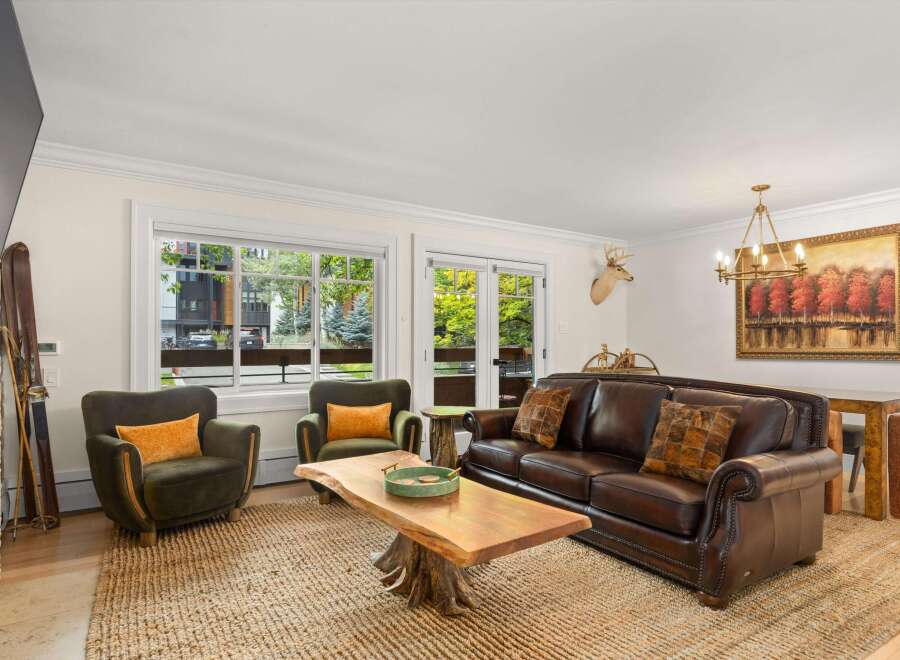 Experience rustic charm in this inviting living room, featuring a rich leather sofa and plush green armchairs perfect for cozy evenings.